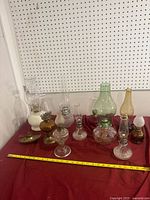 Full group of assorted oil lamps on red cloth with measuring tape