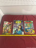 All three comic books side by side with measuring tape