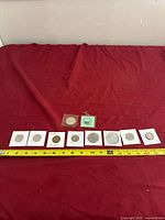 Group of 10 Canadian coins displayed on red cloth with measuring tape