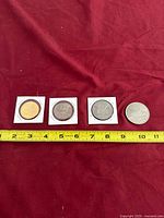 Four coins lined up with measuring tape for scale