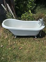 Full view of white clawfoot bathtub with faucet outdoors