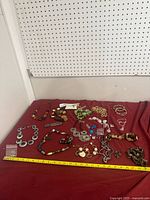 Full lot overview on red surface with measuring tape, showing variety of jewelry