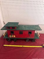 full view of wooden CPR caboose bird feeder with measuring tape showing length