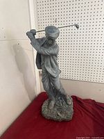 Full view of golfer statue on red cloth backdrop