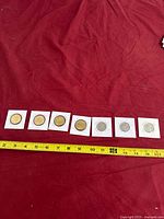 Six King Charles III obverse Canadian coins in flips aligned with measuring tape