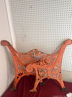 Front view of one ornate orange cast iron bench end