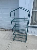 Front view of green four-tier seedling shelf showing full structure