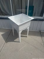 Full front angled view of white plastic laundry tub on legs