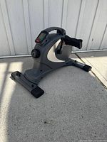 Full view of grey mini pedal exerciser on ground