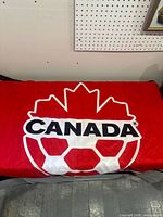 Full view of Canada Soccer flag laid flat showing logo and red field