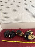 Four gloves laid out with tape measure showing 9-11 in length