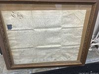 Full view of the framed antique handwritten legal document showing ornate calligraphy text on parchment.