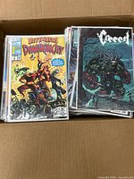 Box containing multiple first issue comic books bagged and boarded with Defenders of Dynatron City and Creept visible on top.