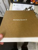 Closed cardboard box lid printed with Meta Quest 3 logo held in hand