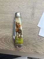 Top view of folded RCMP collectible knife showing handle artwork with mounted police officer on horse and 'RCMP Canada' text.