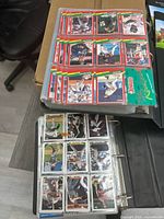 Photo showing two sports card albums open with baseball cards inside plastic sleeves, cards feature various players and colorful backgrounds, mostly Donruss brand.
