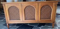 Front view showing three arched lattice speaker panels and tapered legs