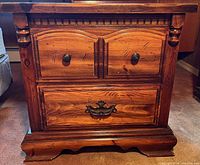 Front view of wooden bedside table showing drawers and hardware