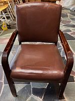 Front view of brown leather armchair showing seat, backrest, and wood arms