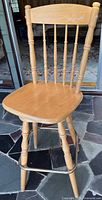 Front view of light wood swivel bar stool with spindle backrest and turned legs