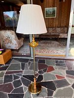 Full view of floor lamp showing base, pole, glass and wood accents, shade