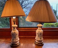 Both ceramic lamps side by side with shades on wooden surface