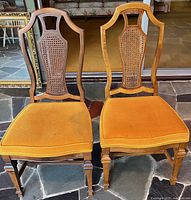 Front view of both chairs showing cane backs and seat upholstery
