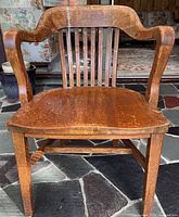 Front view of solid oak armchair showing curved arms, slat back and seat
