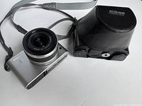 Nikon 1 J1 digital camera with attached 10-30mm lens and included black Nikon carrying case with strap.