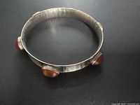 Top angled view of the hammered silver bangle with four amber stones set evenly.