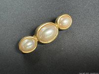Front view of the vintage brooch showing three imitation pearls in gold-tone settings.