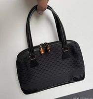 Front view of black micro GG canvas bag with double handles and bamboo zipper pulls