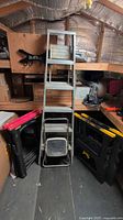 Front view of ladder with step stool nested and four sawhorses stacked around