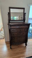Front view of dark walnut dresser with attached mirror, round knobs visible