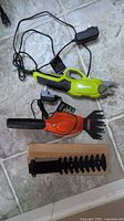 Overall view of Sun Joe pruner, Black+Decker shear, chargers and extra blade