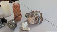 Pillar candle, several stone specimens, sea shell on table