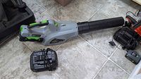Leaf blower with battery attached and charger nearby