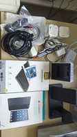 Overview of lot showing both boxed keyboards, digital clock, charging stand, power adapters, cables
