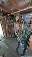 Long-handled tools lined against wall inside shed
