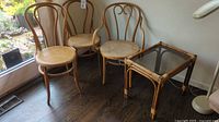 Overall view of three bentwood chairs and bamboo glass-top table