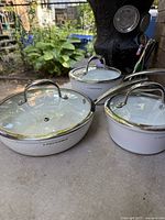 Three white Lagostina frying pans with lids