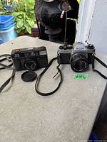 Both Ricoh cameras with straps and loose lens cap on table