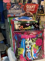 Front view of stacked kids coloring books showing spiral scratch-art book and Jurassic World book