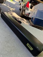 Front angled view of LG SK1 sound bar with attached power cord visible