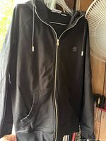 Front view of black Timberland full-zip hoodie on hanger