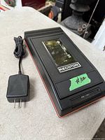 Top view of Recoton VHS tape rewinder and included AC adapter