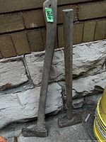 Axe and sledge hammer leaning against wall showing full length and heads