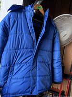 Front view of blue Calvin Klein puffer jacket on hanger showing zip and snap closure
