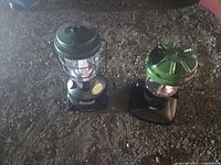 Two Coleman lanterns side by side on ground