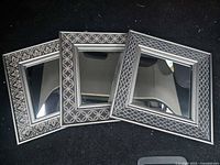 Front view of three matching mirrors showing patterned frames and mirrored centers